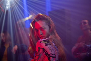 Portrait of a pretty young woman showing dance movements in the night club