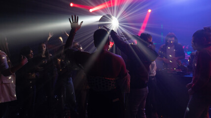 A group of joyful men and women dancing at a nightclub in glowing strobe lights
