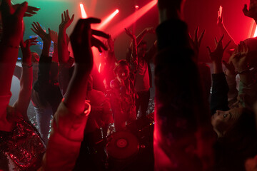 A group of young people dancing with their hands raised in a disco club
