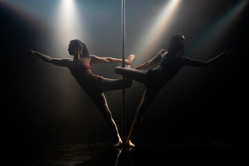 A couple of two young girls doing an acrobatic pole dance. Pole dancing with pylon