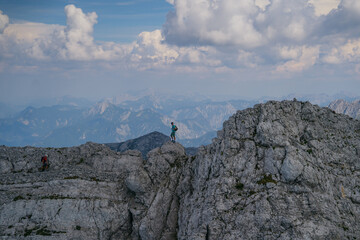 Lone hiker stands on a rocky peak, taking in the breathtaking panoramic views of the distant...