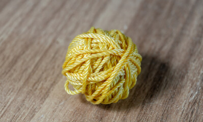 A ball of yellow threads on a wooden surface