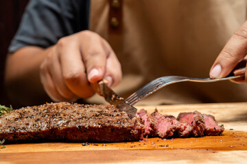 A person is cutting a piece of picanha meat with a knife and fork