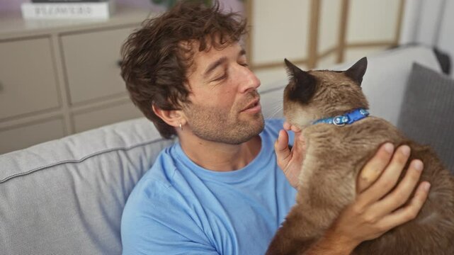 Affectionate man bonding with siamese cat in a cozy living room.