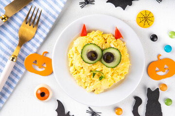 Halloween breakfast scrambled eggs shaped and decorated like cute monster, with fresh vegetables, funny kids Halloween food simple recipe idea