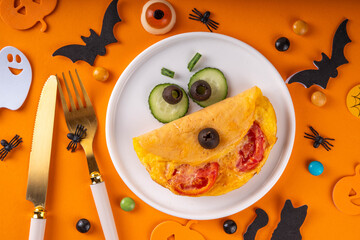 Halloween breakfast eggs omelet shaped and decorated like cute monster, with fresh vegetables, funny kids Halloween food simple recipe idea