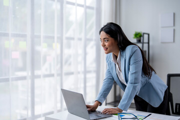 A woman is sitting at a desk with a laptop in front of her