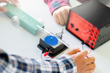Children are studying the measurement of friction force with a spring balance using a small...