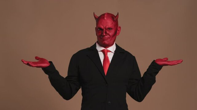 Businessman with red devil makeup gesturing on brown background