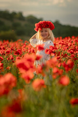 A young girl stands in a field of red flowers, wearing a red flower crown. She is smiling and she is enjoying the beautiful scenery. Concept of joy and appreciation for nature's beauty