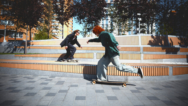 Dynamic image of active guys in stylish clothes in motion, training, riding outdoors on skateboard in public park on sunny day. Concept of sport, activity and movements, hobby