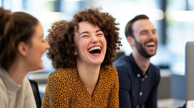 Group of coworkers sharing a lighthearted moment, all smiling and laughing around a desk, the scene filled with a cheerful and positive atmosphere