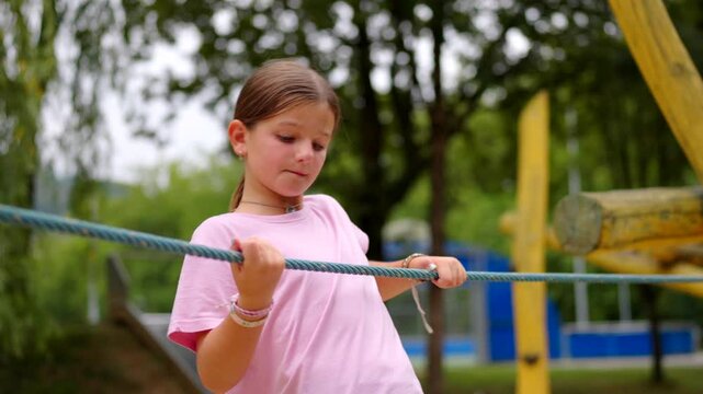 Preteen girl playing in a playpen with a rope