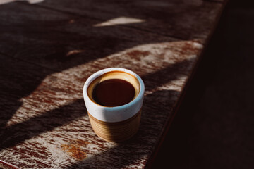 Hot fresh coffee on a wooden table in warm sunlight. The concept of morning coffee before study and work.