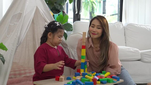 A young autistic child plays with their mother at home, engaged in a joyful and focused activity, surrounded by warmth and love.