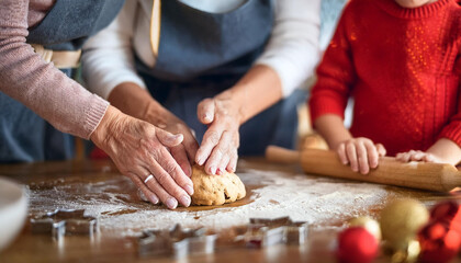 Happy multiracial kid help grandmother to cook Christmas cookies in kitchen during winter holidays
