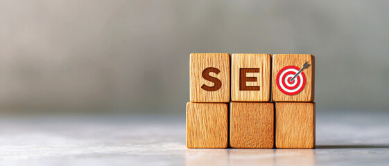 Wooden blocks with SEO letters and a target symbol. Gray background. Concept of search engine optimization and digital marketing.
