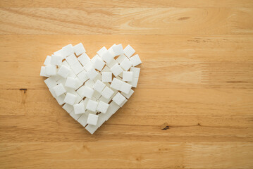 Flat lay heart shape made of sugar cubes on wooden table background with copy space. Healthy...