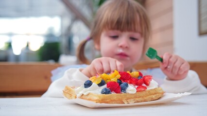Cute Adorable Caucasian Child Girl Eating Delicious Dessert Waffle with Sweet Whipped Cream and...