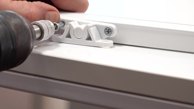 Close up view of gripper lock mechanism screwing to flyscreen window frame with a drill.