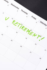 Hand fills in a large wall calendar, counting down the days until retirement, writing 'Retirement'. Concept of early retirement, the Financial Independence, Retire Early movement (FIRE)