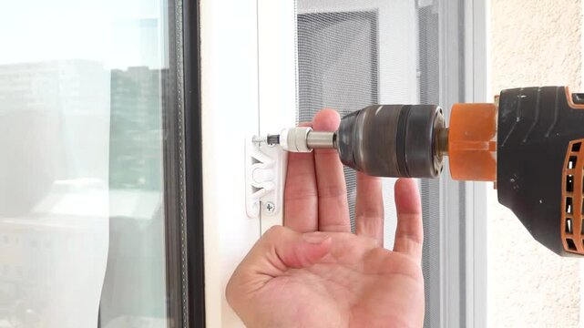 Close up view of snap lock mechanism screwing to fly screen window with an electric drill.