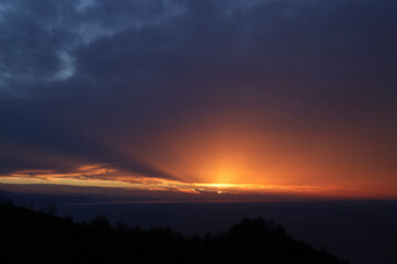 Breathtaking sunrise over mountain range with vibrant colors and sun rays breaking through clouds, serene and inspiring atmosphere. Gonio, Adjara, Georgia. Sundown on Caucasian mountain and Black Sea.