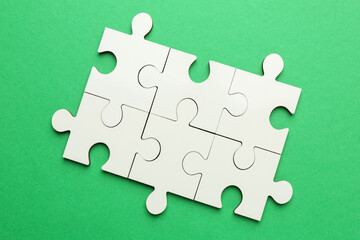 Fototapeta premium White puzzle pieces on green background, top view