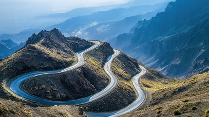 Close-up of a dramatic mountain road with switchbacks, leading to a summit with sweeping views of the expansive landscape below. -