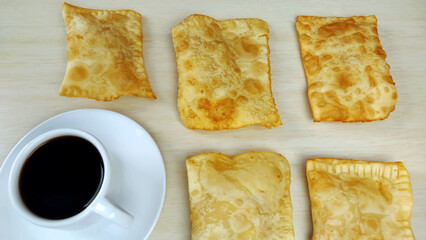 Five  brazilian pastries called pastel on the plate and cup of coffee on the table with copy space
