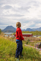 Happy children with parents and dog, european family, hiking the Kvalvika trail on hill at Kvalvika beach, Norway