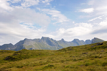 Happy children with parents and dog, european family, hiking the Kvalvika trail on hill at Kvalvika beach, Norway