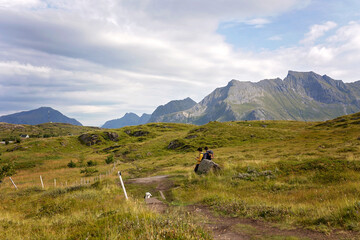 Happy children with parents and dog, european family, hiking the Kvalvika trail on hill at Kvalvika beach, Norway