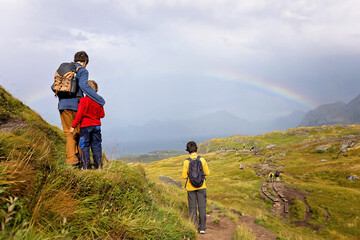 Happy children with parents and dog, european family, hiking the Kvalvika trail on hill at Kvalvika beach, Norway