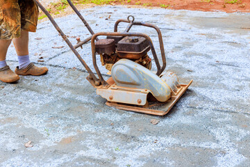 Fototapeta premium Vibratory tamping machine compacting sand during construction of pool platform