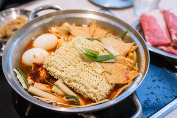 Korean Instant Tteokbokki with Ramen Noodles and Blurred Beef Background