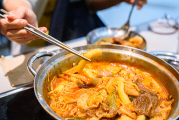 Korean Instant Tteokbokki with Ramen Noodles and Blurred Beef Background