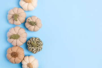 Obraz premium Knitted green, gray and beige pumpkins on blue background with place for text. Concept of autumn, Halloween, Thanksgiving. Handmade work. Flat lay, copy space