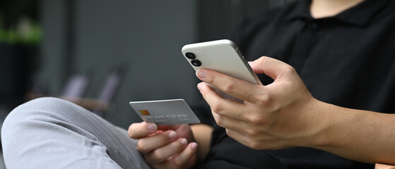 Close-up view of a man shopping online with a credit card and smartphone