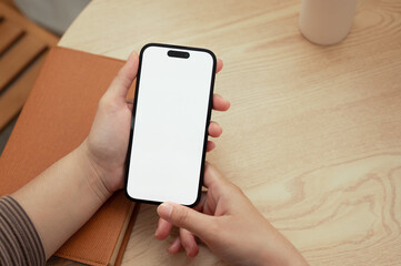 Young woman holding smartphone with empty screen over wooden table