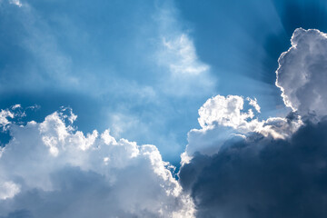 The sky is blue with clouds and the sun is shining through them