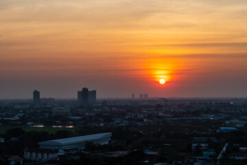 The sun is setting over a city with tall buildings in the background