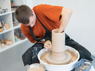 A potter works on a potter's wheel to smooth the surface of a vase.