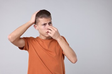 Young man suffering from sinusitis on light grey background, space for text