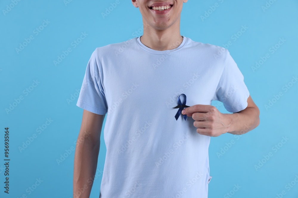 Wall mural prostate cancer awareness. man with blue ribbon and fake mustache on color background, closeup