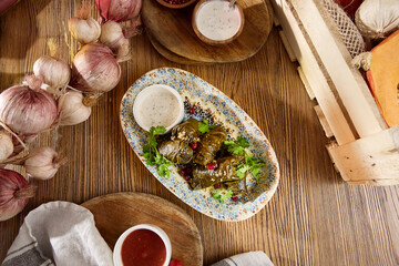 Dolma in Grape Leaves Traditional Mediterranean Cuisine with Dipping Sauces on Rustic Wooden Table