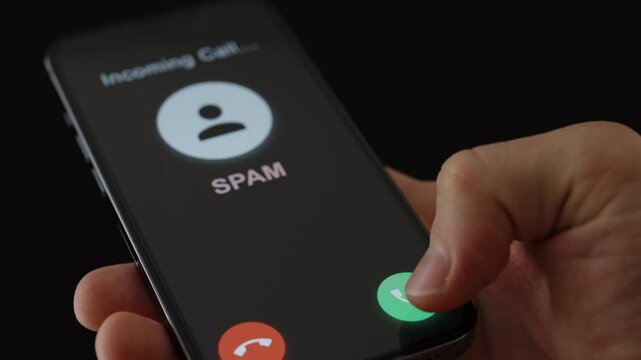 A man chooses to accept or reject a cell phone call marked Spam, from scammers or con artists.