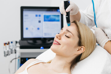 A cosmetologist performs hydropeeling, deeply cleansing and rejuvenating the client's skin in a...