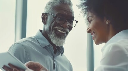 Two colleagues share a light-hearted moment, as they engage with a mobile device, bringing a touch of joy to their professional setting.