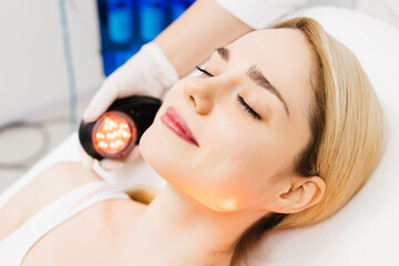 A cosmetologist performs LED light therapy for facial rejuvenation. This non-invasive treatment improves skin elasticity, reduces aging signs, and enhances overall skin radiance.